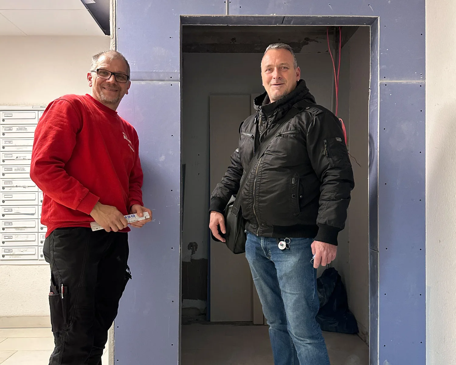 Zwei Handwerker bei der Elektrosanierung im Hausflur